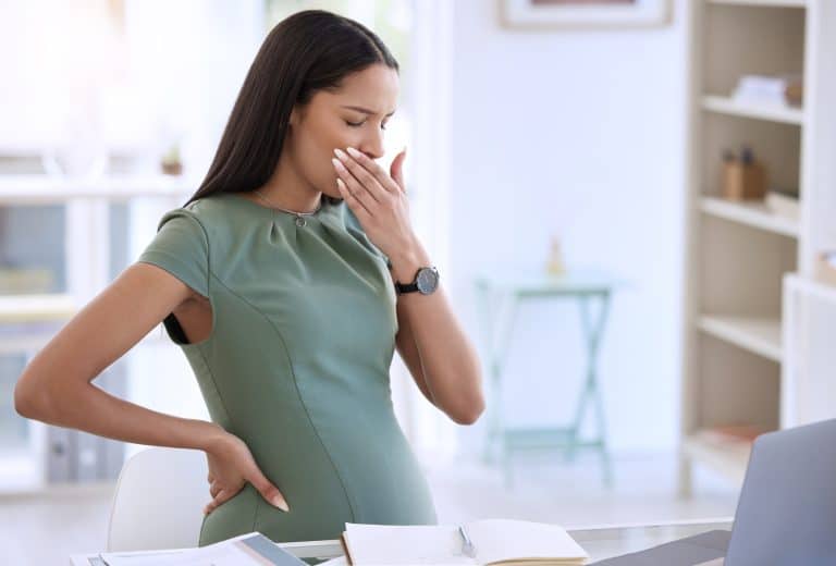 Shot of a young pregnant businesswoman sitting alone in her office and covering her mouth with her hand